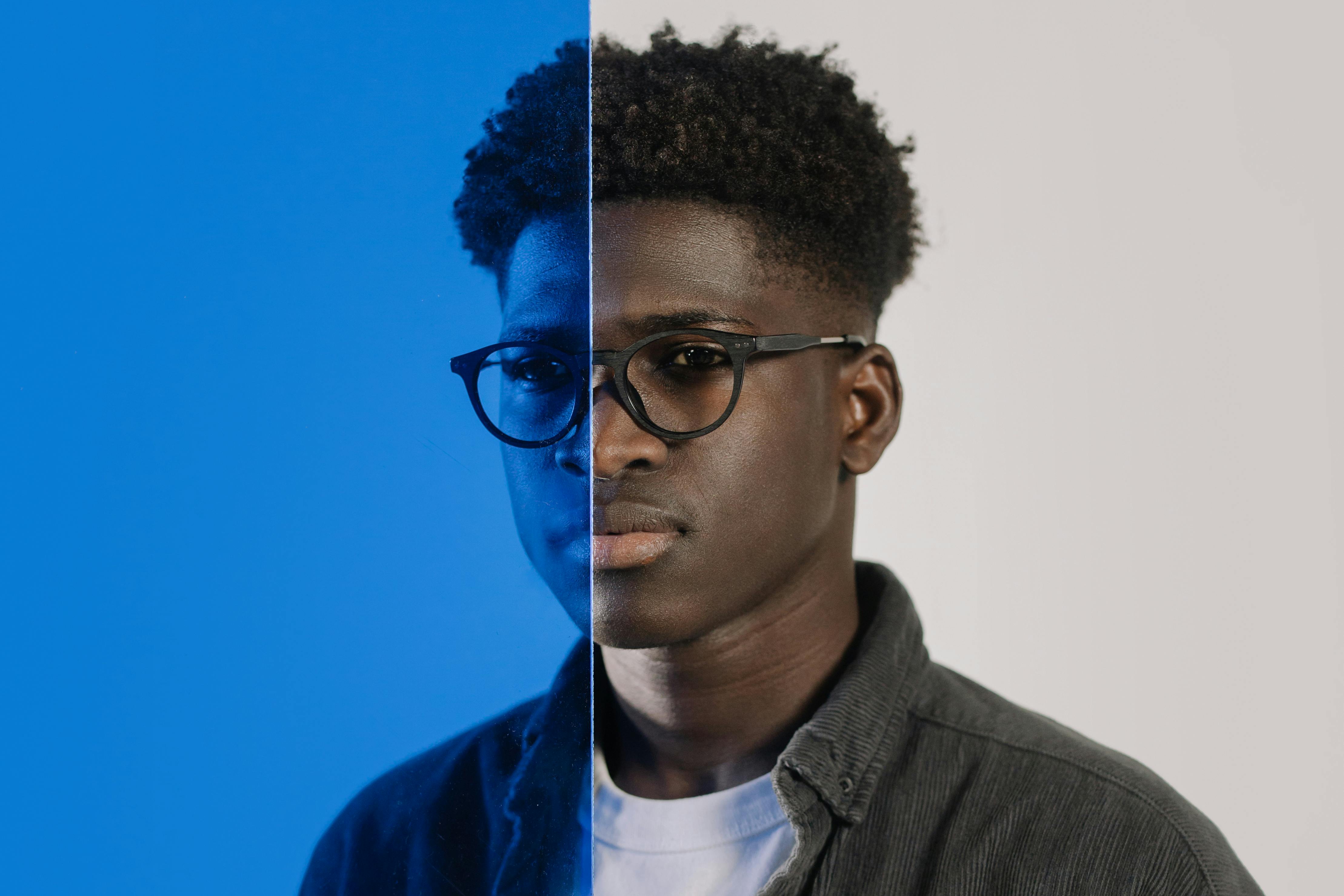 Artistic portrait of a young man with a split blue and white background effect.